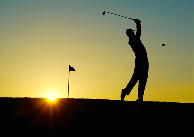 Golfer hitting a golf ball at sunset
