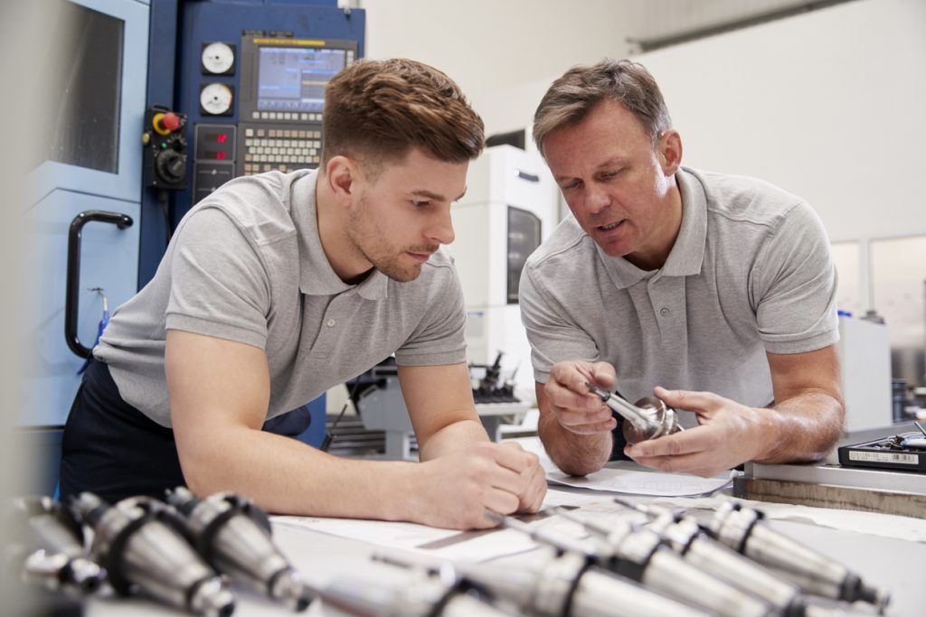 Engineer Showing Apprentice How To Measure CAD Drawings