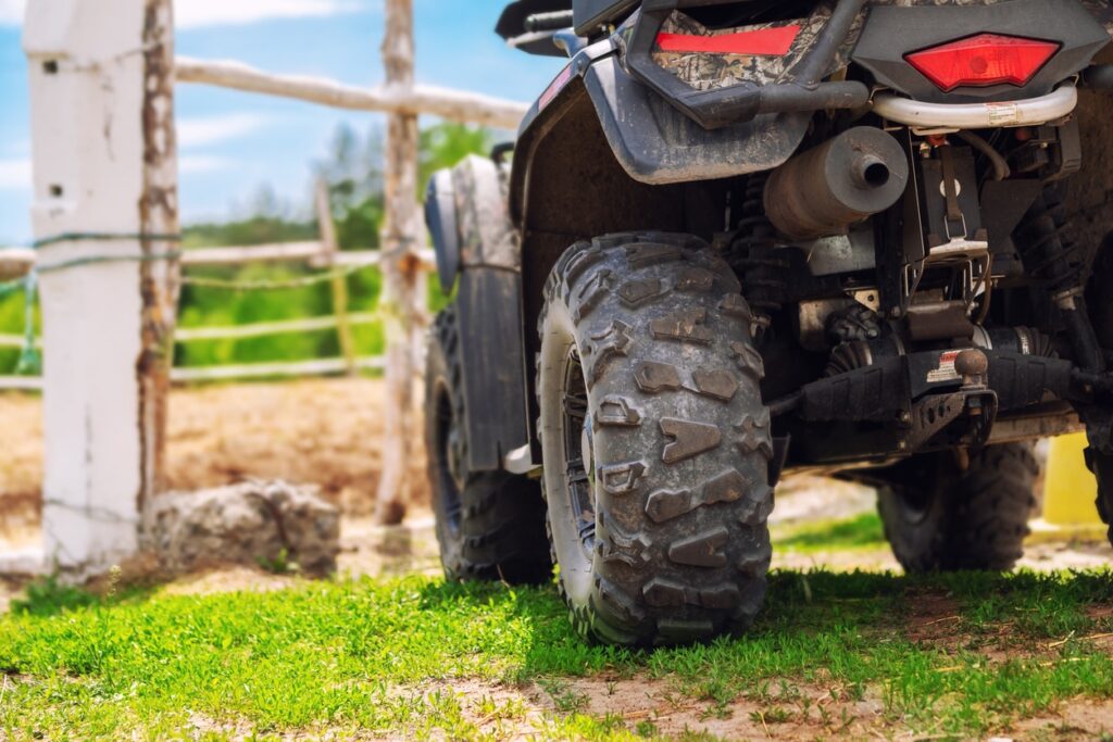 quad bike vehicle standing near wooden fence at farm or horse stable