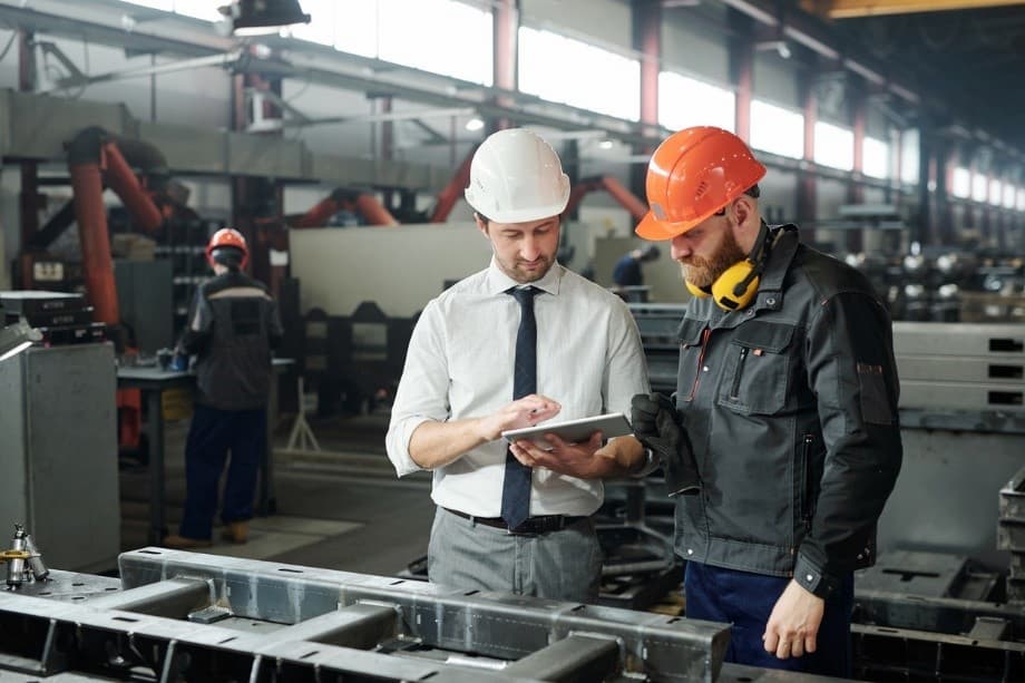 A person in a hard hat looking at a person in a tablet